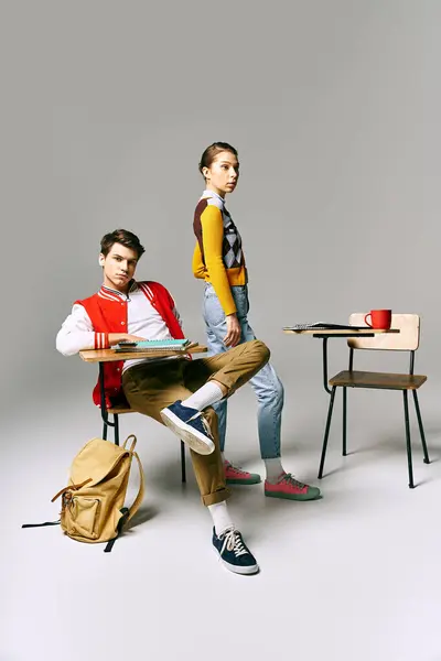 A man and a woman, college students, sit on a desk in a classroom, engrossed in conversation. — Stock Photo