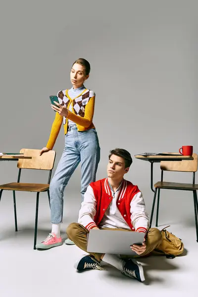 Young male and female students working on a laptop while sitting on the floor in a classroom. — Stock Photo