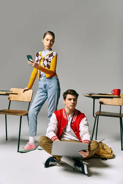 A young male and female students sit on the floor with a laptop, collaborating on a project. — Stock Photo