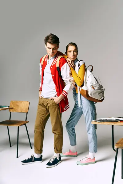 Attractive male and female students standing in front of a desk in a college classroom. — Stock Photo