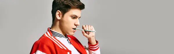 A man in a red jacket posing in college with pen in hand. — Stock Photo