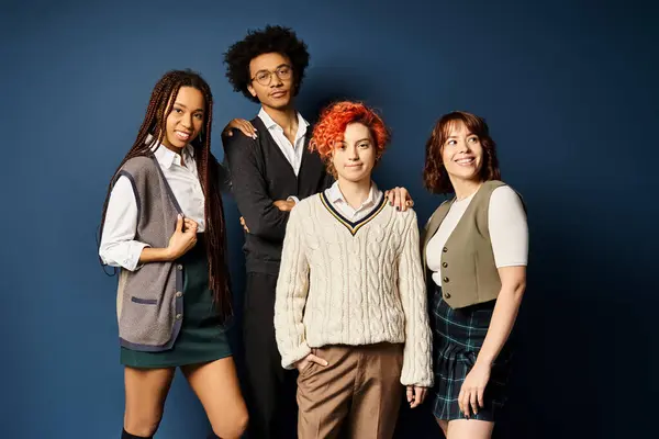 A group of young multicultural friends, including a nonbinary person, standing together in stylish attire on a dark blue background. — Stock Photo