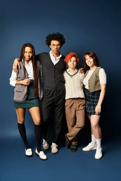 A diverse group of young friends, including a nonbinary person, standing in stylish attire against a dark blue background. — Stock Photo