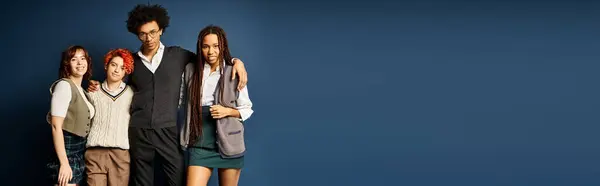 Les jeunes amis multiculturels, y compris un individu non binaire, se tiennent ensemble dans une tenue élégante sur un fond bleu foncé. — Photo de stock