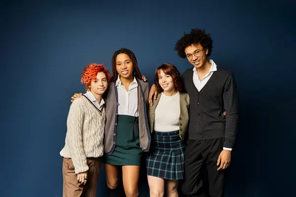 Multicultural friends, standing together in stylish attire on a dark blue background. — Stock Photo