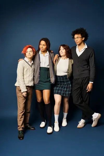 Un groupe de jeunes amis divers et élégants, y compris une personne non binaire, debout ensemble sur un fond bleu foncé. — Photo de stock