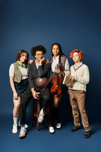 Um grupo diversificado de jovens amigos, incluindo um indivíduo não binário, estão em trajes de moda contra um pano de fundo azul escuro. — Fotografia de Stock