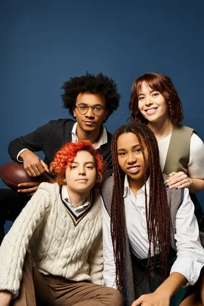 Un groupe diversifié de jeunes amis, y compris une personne non binaire, s'assoient étroitement ensemble dans une tenue élégante sur un fond bleu foncé. — Photo de stock