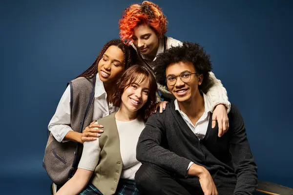 Diverse group of young friends in stylish attire strike a pose together on a dark blue background. — Stock Photo