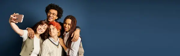 A diverse group of young multicultural friends, including a nonbinary person, standing together in stylish attire on a dark blue background. — Stock Photo
