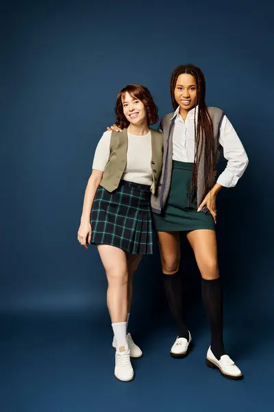 Young women standing united in stylish attire against a dark blue background. — Stock Photo