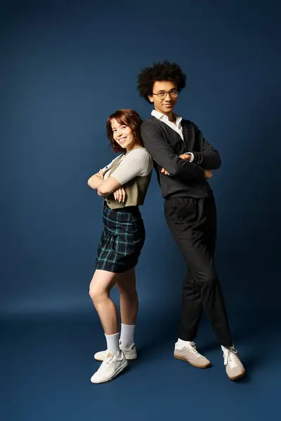 Un jeune homme et une jeune femme élégants, posent ensemble sur un fond bleu foncé. — Photo de stock