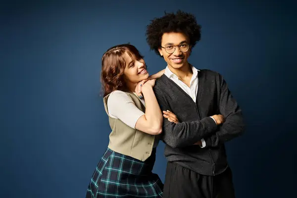 A young multicultural duo standing together in stylish attire on a dark blue background. — Stock Photo