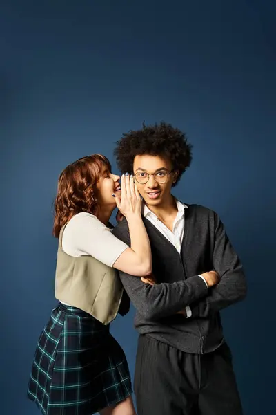 A young multicultural man, a woman, stand together in stylish attire against a dark blue background. — Stock Photo