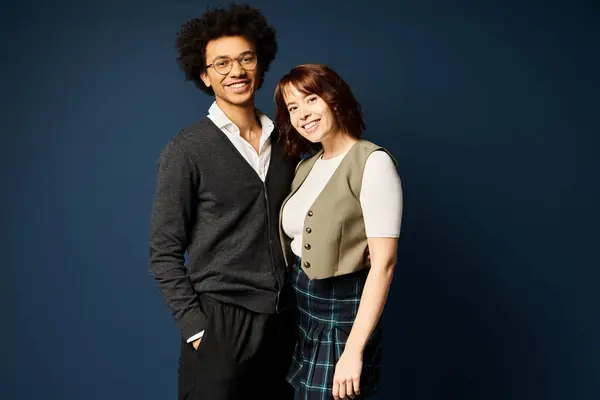 Un giovane duo multiculturale si unisce in abiti eleganti su uno sfondo blu scuro. — Foto stock