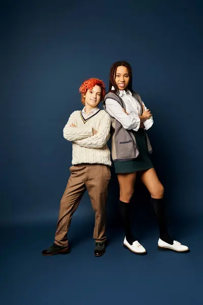 Young friends, including a nonbinary person, stand together in stylish attire against a dark blue background. — Stock Photo