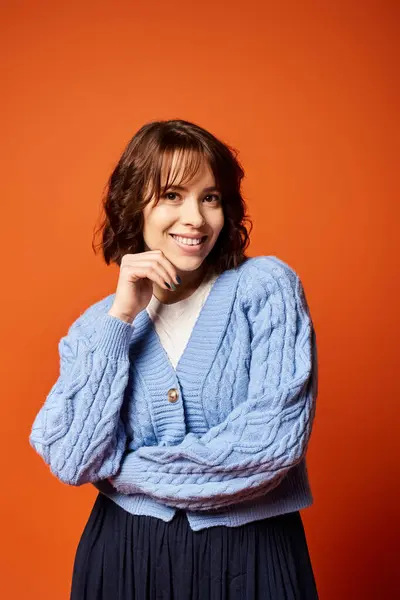 A young woman in a blue cardigan poses confidently, radiating elegance and grace in a studio setting. — Stock Photo