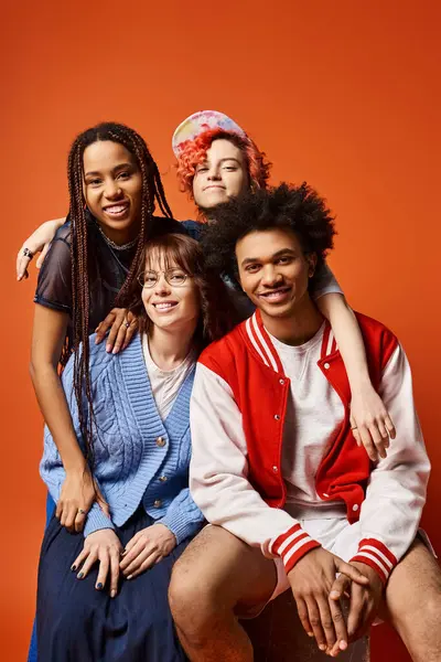 Interracial young friends, including a nonbinary individual, sitting closely together in a studio setting in fashionable attire. — Stock Photo