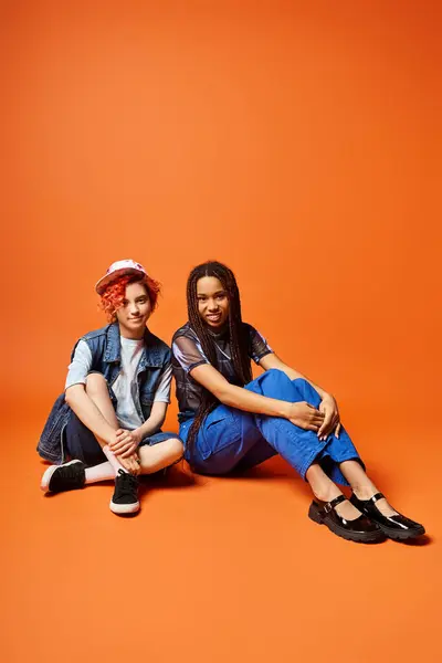 A diverse couple sitting on the ground, bonded in friendship and togetherness, showcasing unity and diversity. — Stock Photo