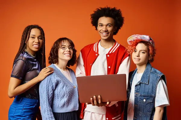 Jovens amigos multiculturais, incluindo uma pessoa não binária, de pé juntos em trajes elegantes com laptop em um ambiente de estúdio, incorporando unidade e diversidade. — Fotografia de Stock