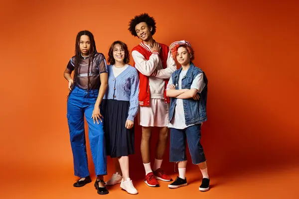 A group of young multicultural friends, including a nonbinary person, stand closely together in stylish attire in a studio setting. — Stock Photo
