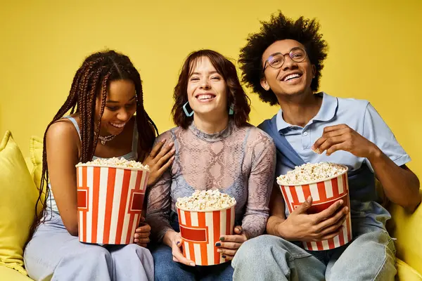 Eine bunte Gruppe von Freunden in stylischer Kleidung sitzt auf einer Couch und hält Popcorn-Eimer in der Hand. — Stockfoto