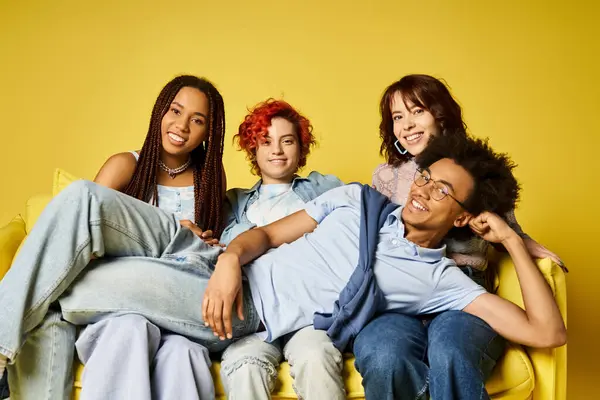 A diverse group of friends sits together on a vibrant yellow couch in a stylish studio setting. — Stock Photo