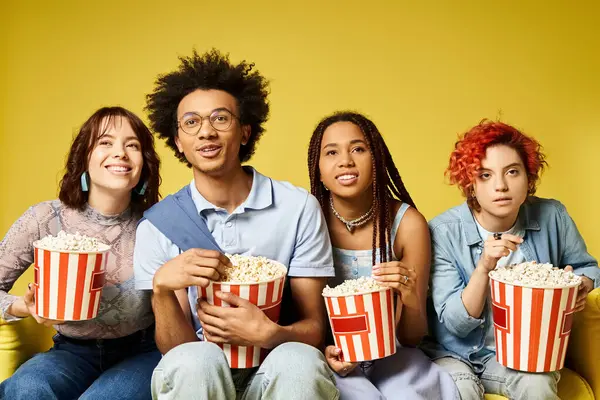 A diverse group of friends in trendy clothing sitting closely, holding buckets of popcorn for a fun movie night. — Stock Photo