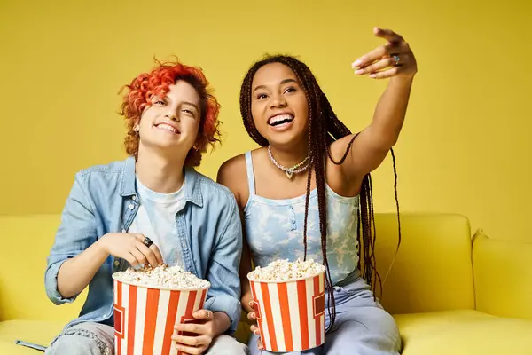 Multicultural friends, one nonbinary, relaxing on a couch in stylish attire, exuding warmth and togetherness. — Stock Photo