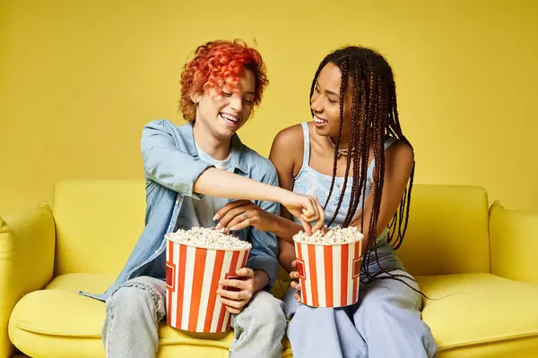 Stylish young friends lounging on a vibrant yellow couch together, showcasing diversity and friendship. — Stock Photo