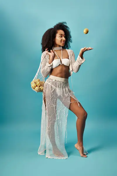 Beautiful African American woman looks elegant posing with a fruit in her hand. — Foto stock
