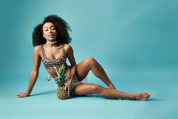 Elegante donna afroamericana in bikini che colpisce una posa con un ananas. — Foto stock