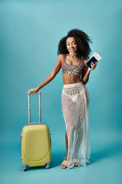 Mujer joven con maleta y pasaporte posando sobre fondo azul - foto de stock