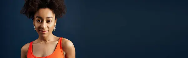 A young woman with curly hairdo smiling against a vibrant blue backdrop. — Stock Photo