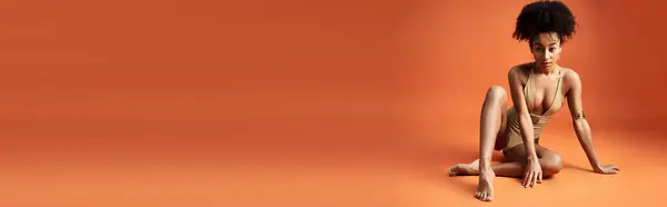 A young African American woman strikes a stylish pose against an orange background. — Stock Photo