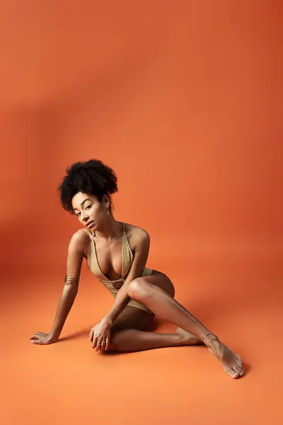 Приваблива афроамериканська жінка позує в стильному бікіні на яскравому помаранчевому тлі. — стокове фото
