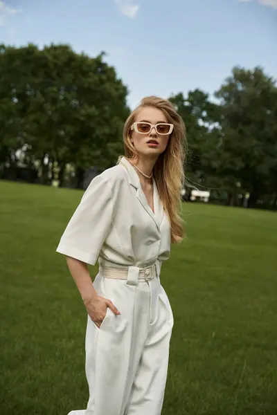 A graceful woman exudes elegance in a white jumpsuit and stylish sunglasses, embodying chic and sophistication. — Stock Photo