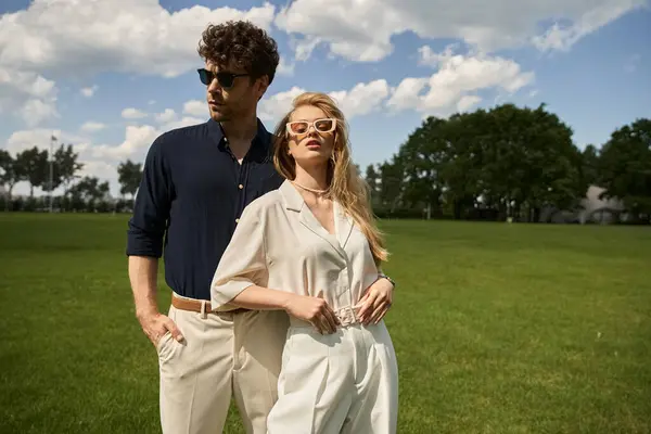 A beautiful young couple dressed elegantly, basking in the serenity of a green field. — Stock Photo
