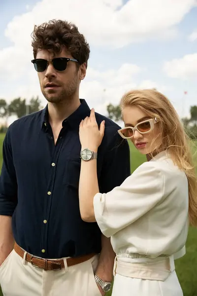 Ein stilvoller, wohlhabender Mann und eine Frau mit Sonnenbrille in einem üppigen Feld, die einen Hauch von Raffinesse und Luxus verströmen. — Stockfoto