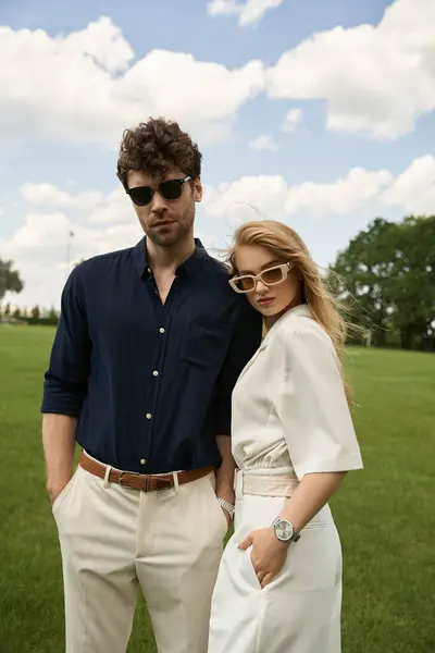 A stylish man and woman strike a pose in a lush field, showcasing their refined clothing and old money charm. — Stock Photo