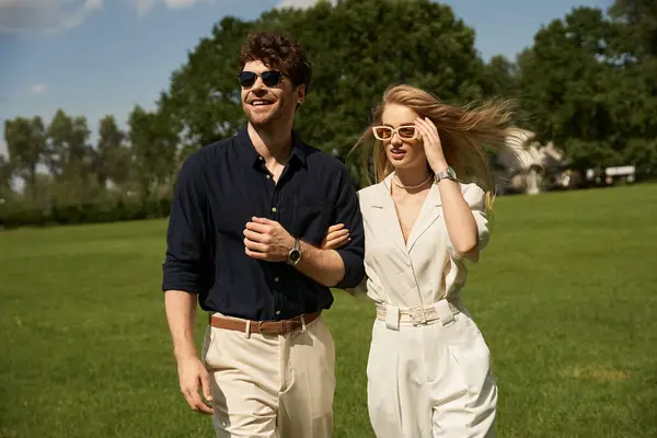 Красива молода пара в елегантному одязі прогулюється крізь пишне зелене поле в експозиції старомодного стилю і насиченого способу життя. — стокове фото