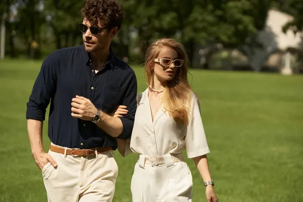 A stylish, well-dressed man and woman leisurely walk in a lush park, embodying a classic, affluent lifestyle. — Stock Photo