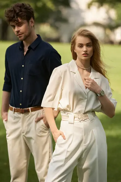 A stylish young couple in elegant attire standing in a lush park, exuding an air of old money sophistication. — стокове фото