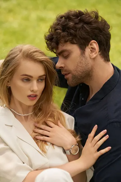 Um belo jovem casal em roupas elegantes sentados juntos em um campo gramado, desfrutando uns dos outros companhia ao ar livre. — Fotografia de Stock