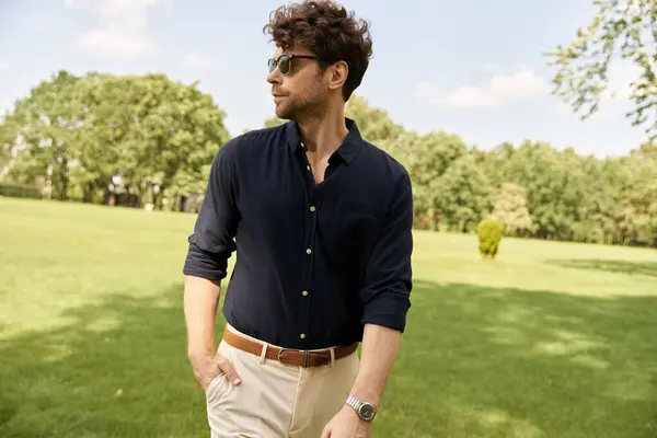 Un homme en chemise bleue et pantalon bronzé se promène paisiblement dans un parc, entouré de verdure et de nature beauté. — Photo de stock