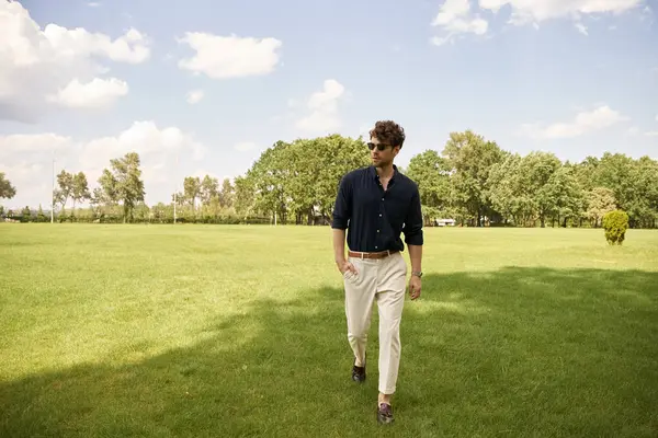 A man strolls through a lush grassy field under a clear sky, soaking in the peace and tranquility of nature. — Stock Photo