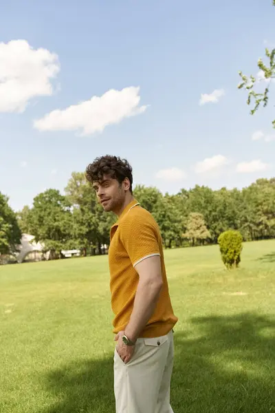 Um homem de camisa amarela está graciosamente em um campo gramado exuberante. — Fotografia de Stock