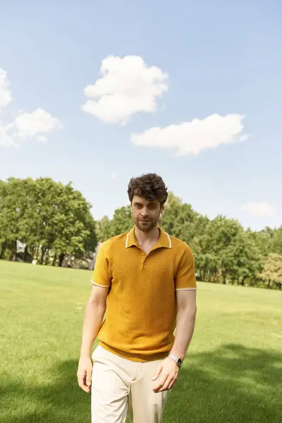 A man in a yellow polo shirt walks gracefully through a vibrant field. — Stock Photo