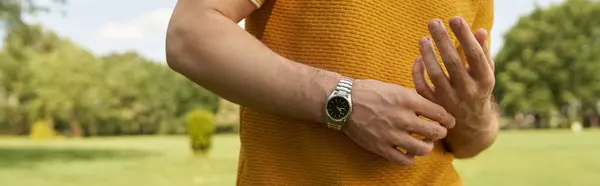 A stylish man with watch surrounded by nature in a park setting. — Stock Photo