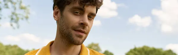 A man in a yellow shirt stares at the camera, his expression intense and captivating. — Stock Photo